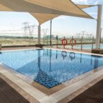 Outdoor swimming pool with sun shade in Dubai, showcasing a pleasant outdoor atmosphere.